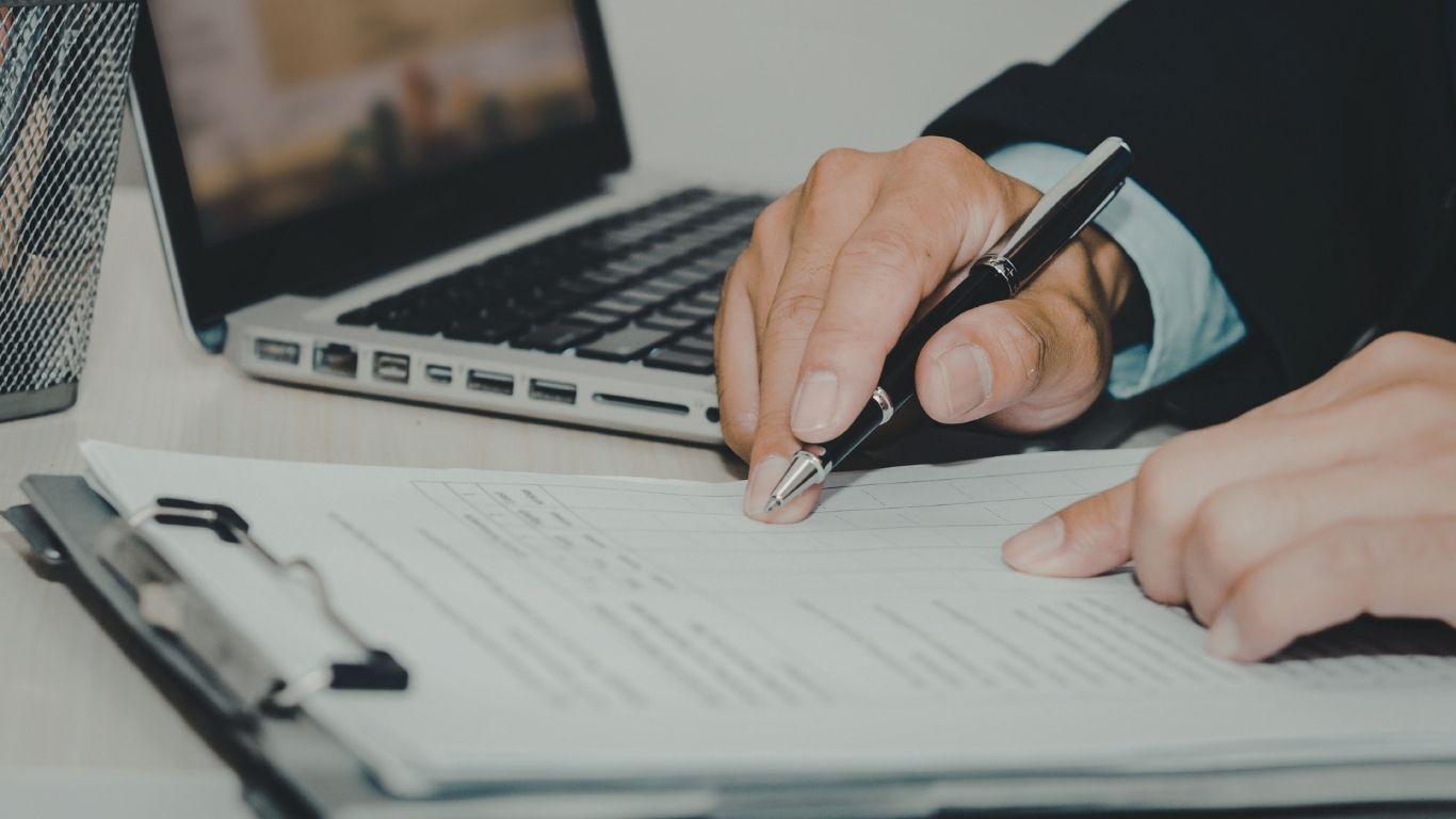 An auditor checking paperwork with a pen during a Post-Closing audit.