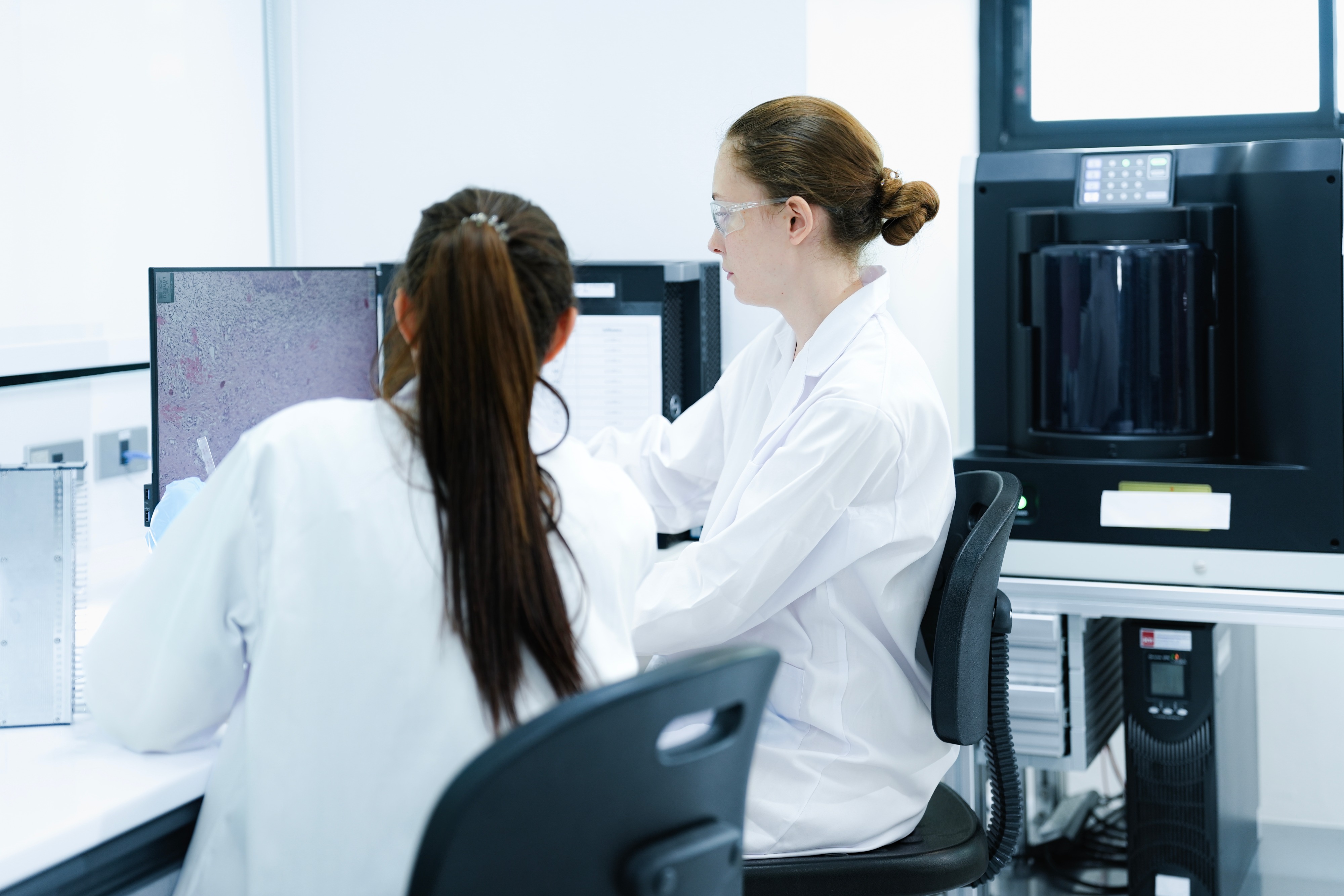 Scientists reviewing data on multiple monitors. The emphasis is endpoint interpretation and data analysis rather than laboratory procedures.